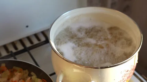 A close-up shot of a pot of boiling water with pasta on a gas stove in the .. Video stock 345751040