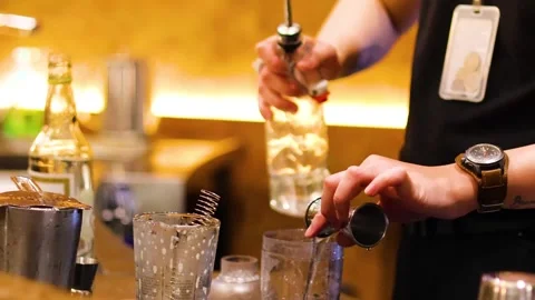 A close up shot of a professional bartender's hands skillfully pouring liqu.. Vidéo 332749733