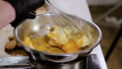Close-up shot of professional chef mixing eggs and butter with whisk in bowl. 4K Stock Footage 136490262