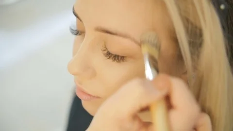 Close up shot of professional make-up artist applying makeup on the face of the Stock Footage