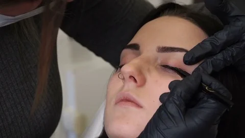 Close up shot. Professional specialist of permanent make-up applying eyeliner Stock Footage 83329438