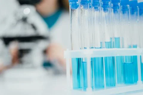 A close-up shot of a rack filled with test tubes containing blue liquid, hi.. Stock Photos