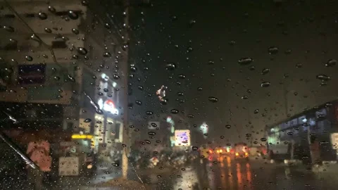 Close up shot of rain drops on car wind shield in city traffic Stock Footage 240602219