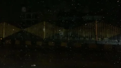 Close up shot of rain drops on car wind shield in city traffic Stock Footage 240602230