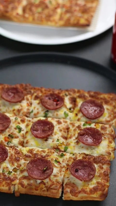 Close-up shot of a rectangular pepperoni pizza with melted cheese Vídeos de archivo 307058517