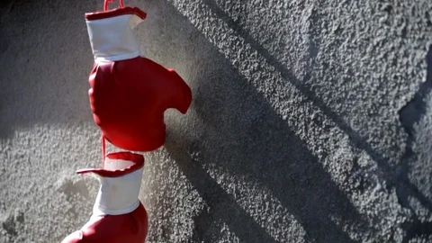 Close-up shot on red boxing gloves hanging on a rough concrete wall Stock Footage 105650174