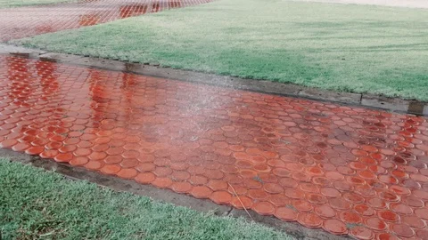 Close up shot of red brick footpath watered by sprinkler system in a park. Stock-Footage 102573372