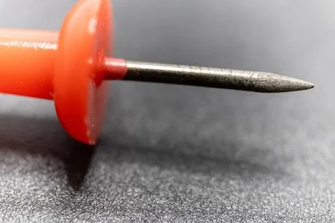 A close-up shot of a red pushpin with a sharp metal point, ready to secure do Stock Photos