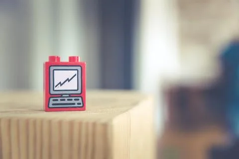A close shot of a red toy with computer picture on it on a wooden surface wit Stock Photos