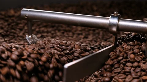 Close-up shot of roasted coffee beans mixing by stirrer on sieve 库存影片 115880298