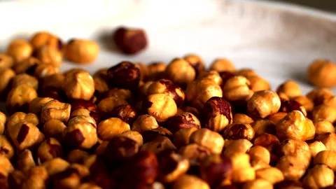 A close-up shot of roasted hazelnuts on a white surface, showcasing their Stock Footage 294344877