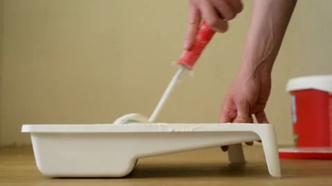 Close-up shot of a roller picking up paint from a plastic tub. CLIP. Home Stock Footage 139768985