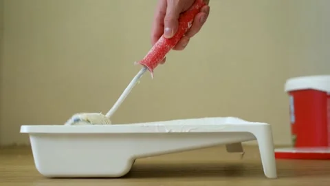 Close-up shot of a roller picking up paint from a plastic tub. Footage. Home Видео 139771783