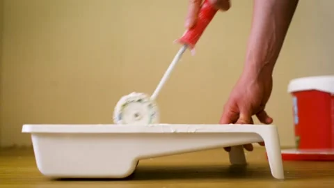 Close-up shot of a roller picking up paint from a plastic tub. Clip Home Stock-Footage 139936732