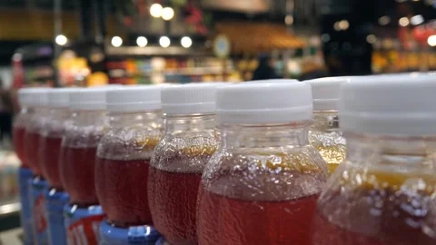 Close-up shot of a row of plastic beverage bottles with white caps, filled with Stock Footage 314707521