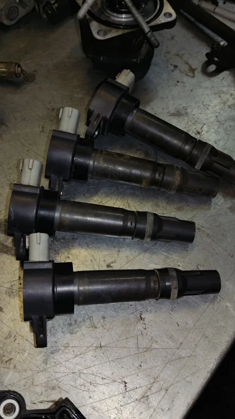 Close-Up Shot of Rusty Ignition Coils Laid Out on Dirty Workshop Surface Stock Footage 346411303
