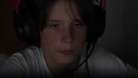 A close-up shot of a sad or tired teenager in gaming headphones looking at .. Stock Footage 339531814
