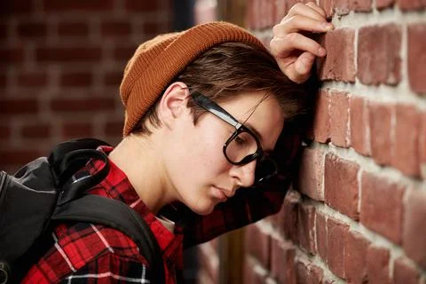 Close-up shot of a sad, pensive teen boy in stylish casual clothes and glasse Stock Photos