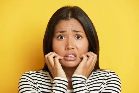 Close up shot of scared Asian brunette woman stares bugged eyes keeps hands near Stock Photos