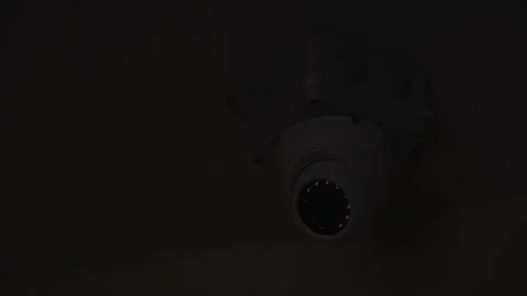 A close-up shot of a security camera installed on a dark ceiling, with infrared Stock Footage 284096505