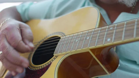 Close shot of senior man strumming on a guitar in his conservatory, in slow moti Stock Footage 136418698