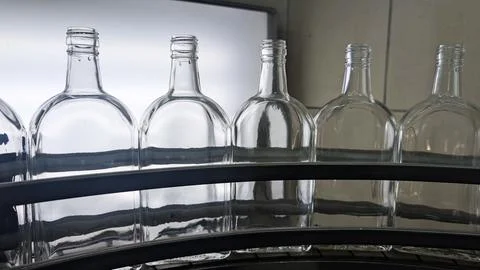 A close-up shot of a set of six empty glass bottles arranged on an assembly.. Stock Photos
