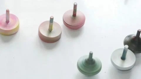 Close-up shot of several spinning plastic toys set on a white table. Stock Footage 146117736