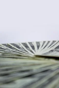 A close-up shot of several US dollar bills arranged in a fan shape, with a wh 写真素材
