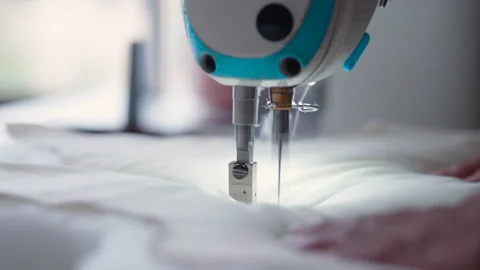 Close-up shot of a sewing machine in action, guiding fabric with its hands Stock Footage 344092091
