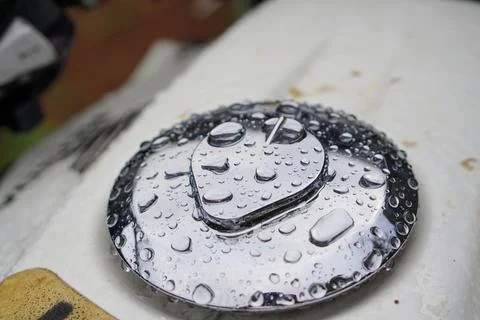 Close-up shot of a shiny chrome motorcycle fuel tank cap covered in clear rain Stock Photos