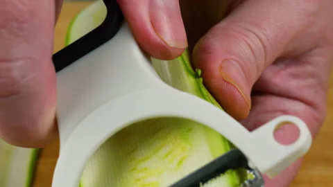A close-up shot shows a chef slicing a fresh green zucchini into long. Stock Footage 341540383
