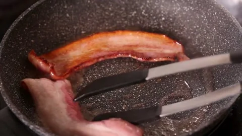 This close up shot shows fresh bacon cooking and sizzling in cast iron pan. 스톡 동영상 334642377