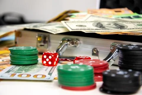 A close-up shot of a silver briefcase with red dice and stacks of casino chip Stock Photos