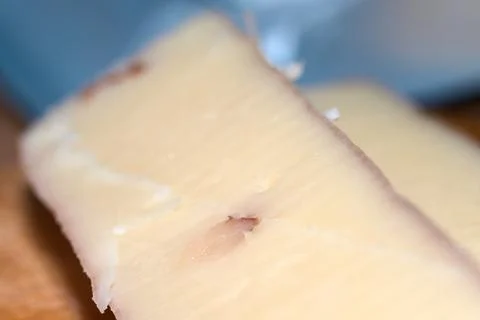 Close-up shot of a slice of artisan hard cheese with walnut embedded inside. Stock Photos