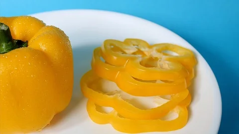 Close of shot of a sliced and one whole yellow capsicum on a white plate Stock Footage 114737173