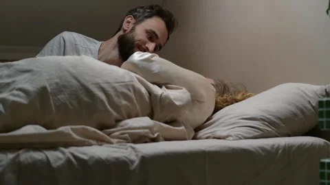 Close up shot from slightly low angle of a young married couple lying in bed. 库存影片 329939735