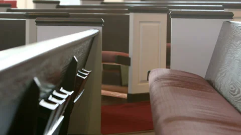 Close-up shot slowly moving past pews in a church Stock Footage