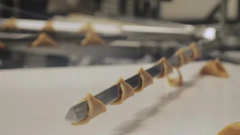 Close-up shot of small triangular dough pieces wrapped around a metal rod on a Stock Footage 327843673