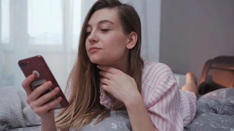 Close-up shot of smiling nice young woman with long hair laying in bed and Video stock 112752044