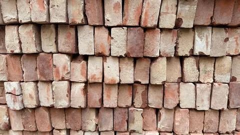 Close up shot of a stack of old, weathered red clay bricks arranged horizonta Foto stock