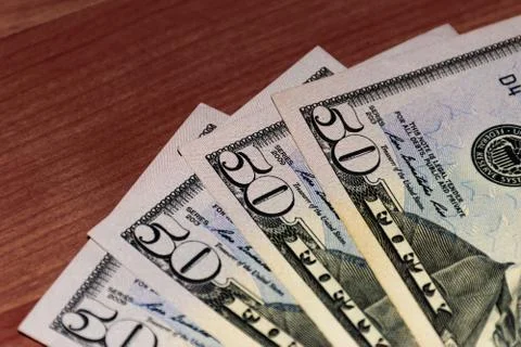 A close-up shot of a stack of several fifty US dollars banknotes on the table Stock Photos