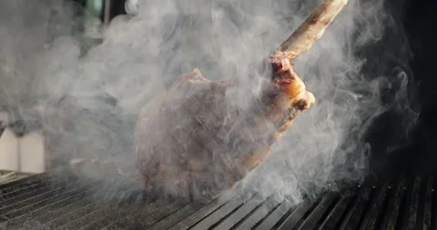 Close-up shot of steak in smoke. Tomahawk steak grilling on barbecue charcoal Stock Footage 271088962