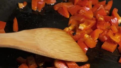 Close up shot of stirring red cut pepper slowly with wooden spoon while frying Stock Footage 244195126