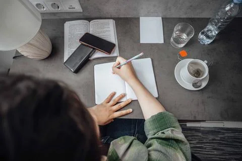 Close-up shot of a student deeply engaged in writing notes, highlighting the Stock Photos