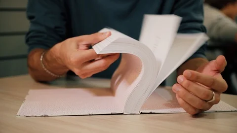Close shot of student's hand opening book and leafing papers in library Stock Footage 118214226