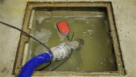 Close-up shot of a sump pump system operating inside a concrete utility pit Stock Footage 314069563