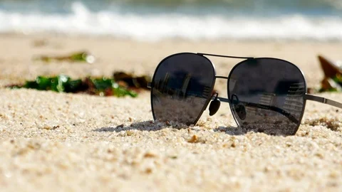 Close up shot of sunglasses on sandy beach on a sunny summer day. Stock Footage 108642679