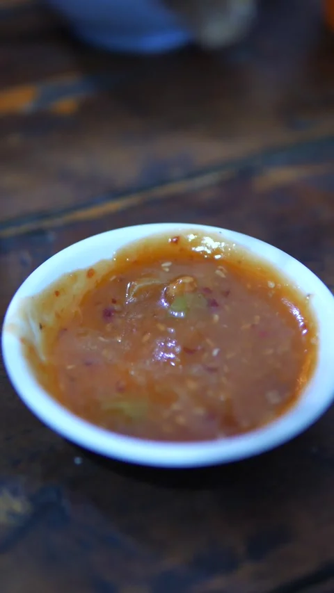 Close-up shot of Thai beef slice dipping in spicy chili sauce Video stock 320768855