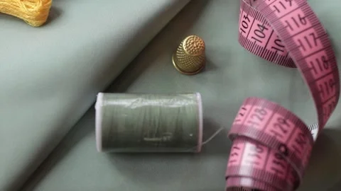 Close up shot of thimble and thread on pastel fabric. Stock Footage 174675563