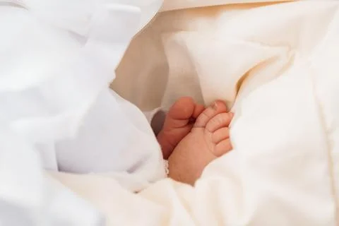 A close-up shot of a tiny baby's foot peeking out from under a soft, white .. Foto stock